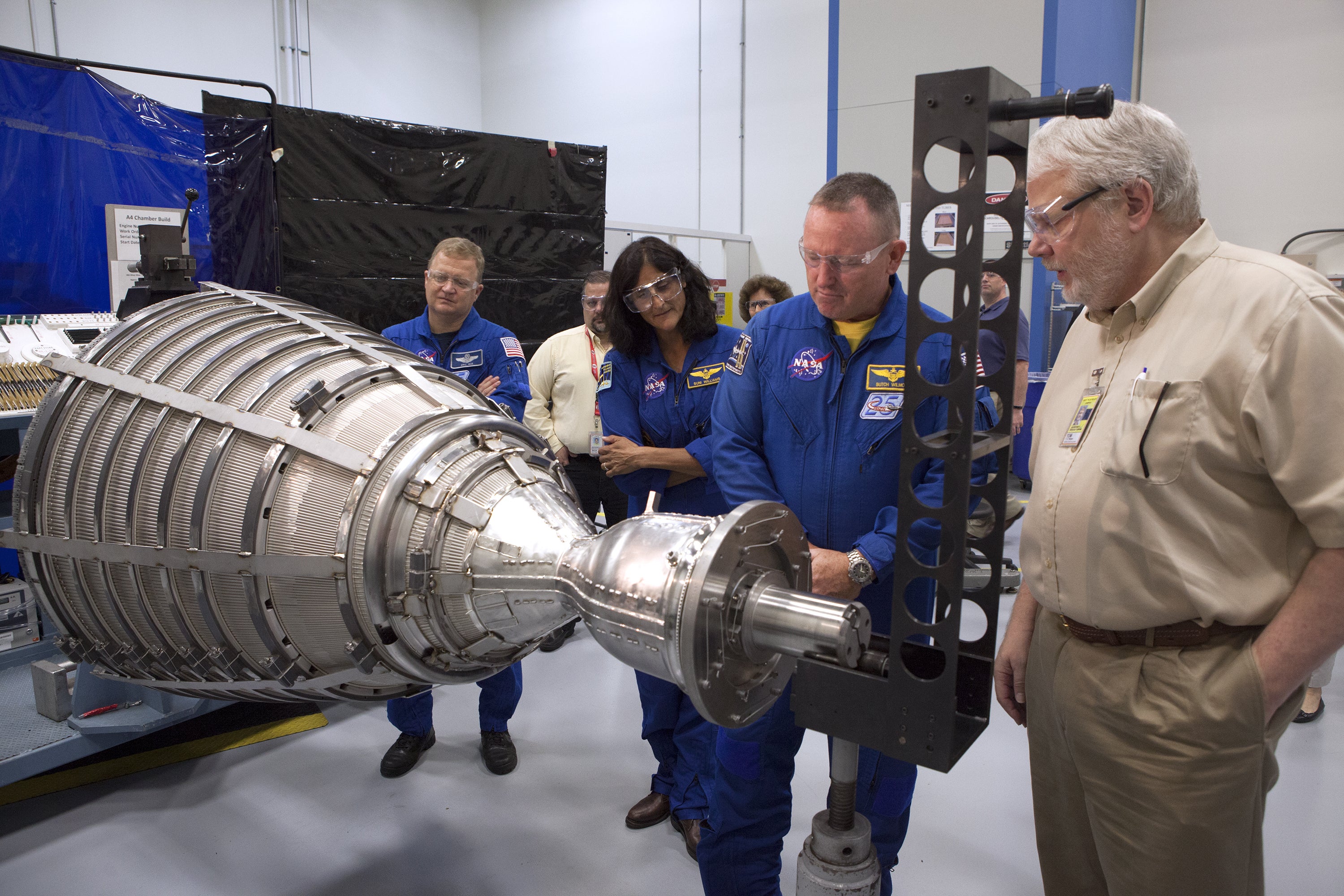 Astronaut and team examine a piece of machinery