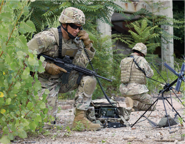 Soldiers use communication devices in the field