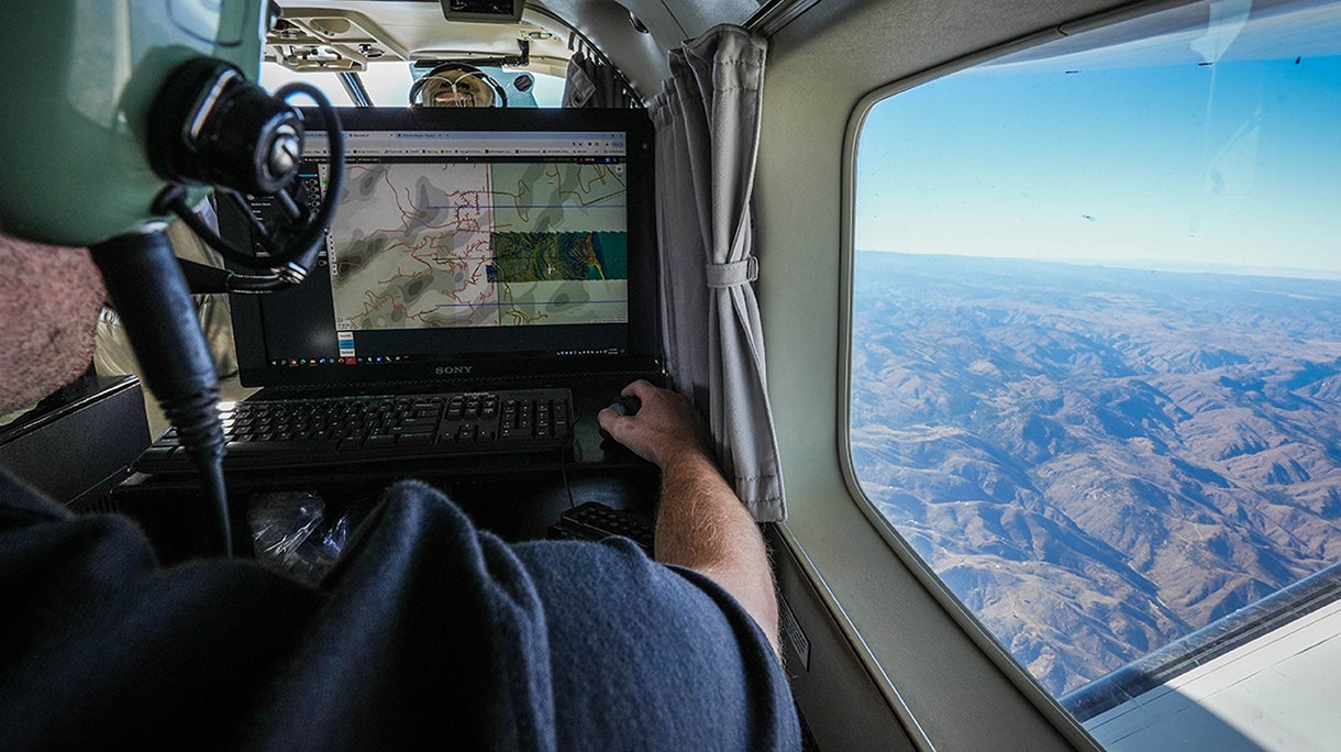 Worker types on laptop while looking out airplane window