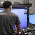 An employee looks at his screen in a T-shirt that says "Proven Propulsion. Fueled by Innovation."