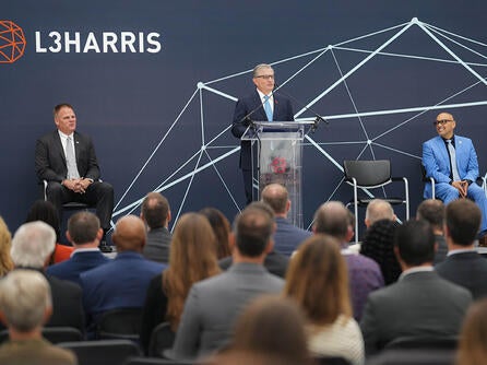 L3Harris Christopher E. Kubasik speaks at a podium at a facility